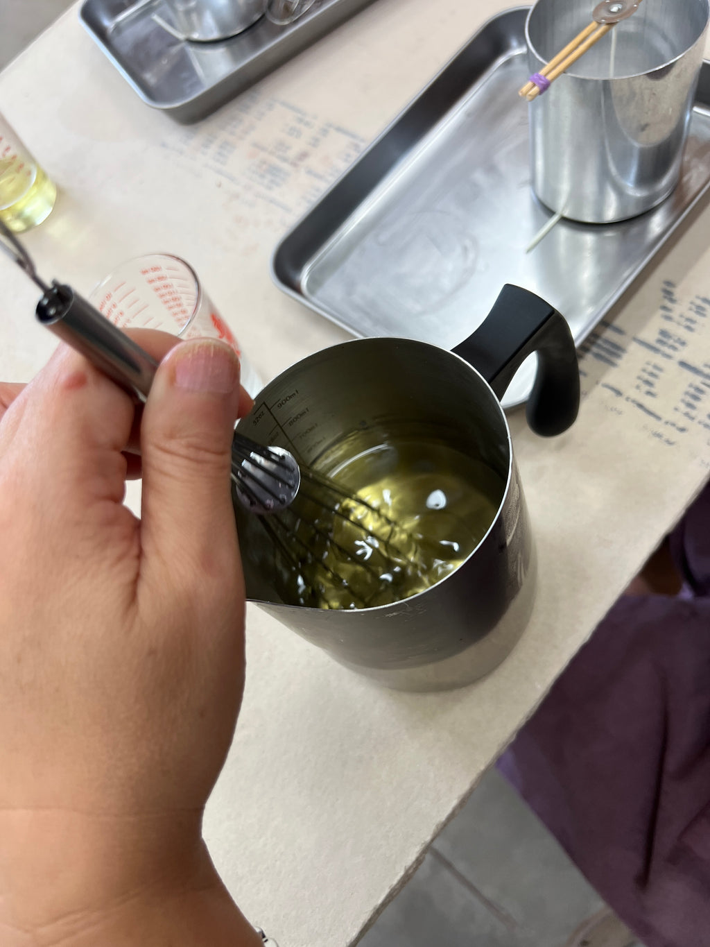 Metallic measuring cup held by a hand with a blurred background