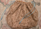 Textured brown drawstring bag on a floral patterned background