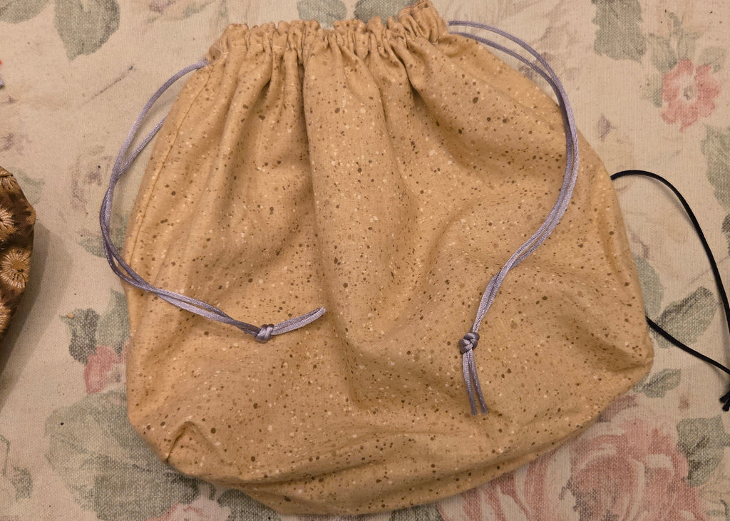 Beige drawstring bag on a floral-patterned surface