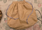 Beige drawstring bag on a floral-patterned surface
