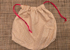 Beige drawstring bag with red string on a textured surface